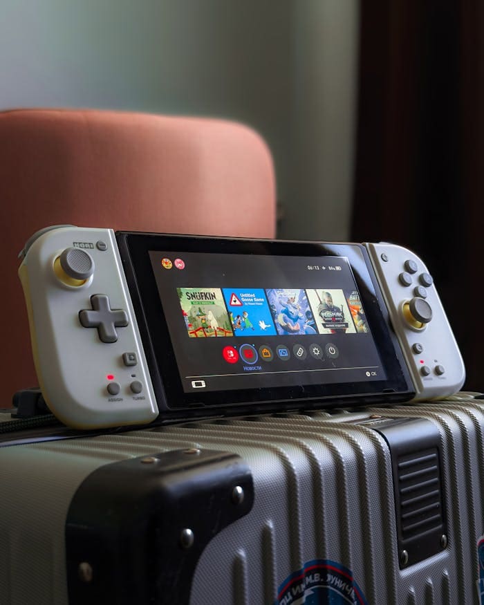 A handheld gaming console rests on a suitcase, ready for travel adventures.