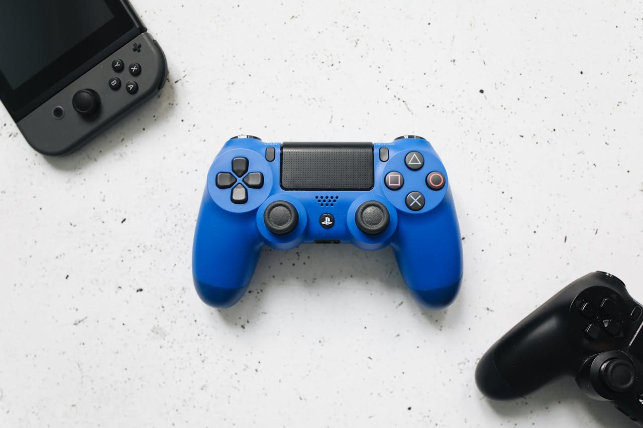 A top view of various colorful gaming controllers on a white surface.